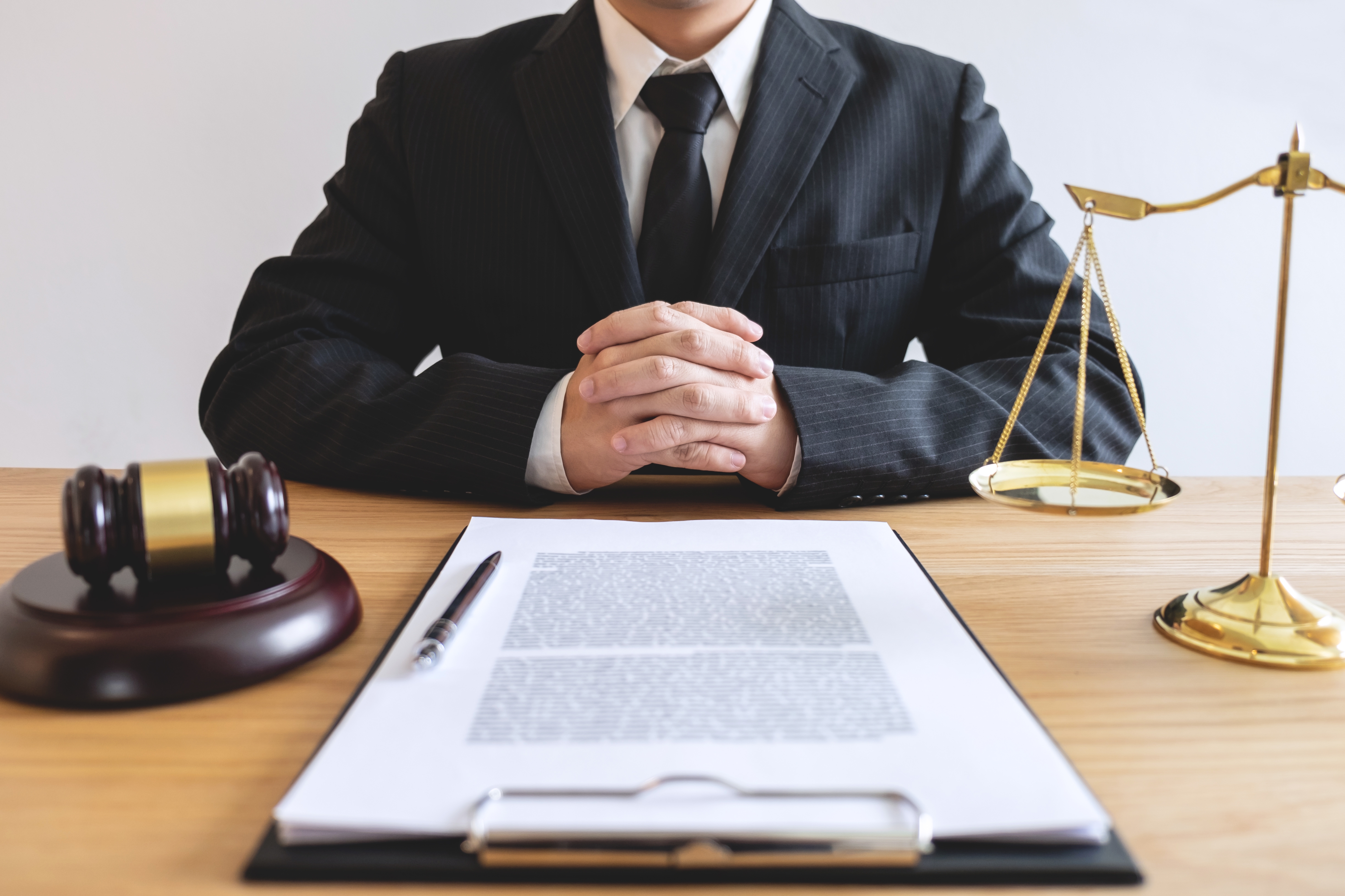 Legal law, advice and justice concept, male lawyer or notary working on a documents and report of the important case and wooden gavel, balance on table in courtroom.