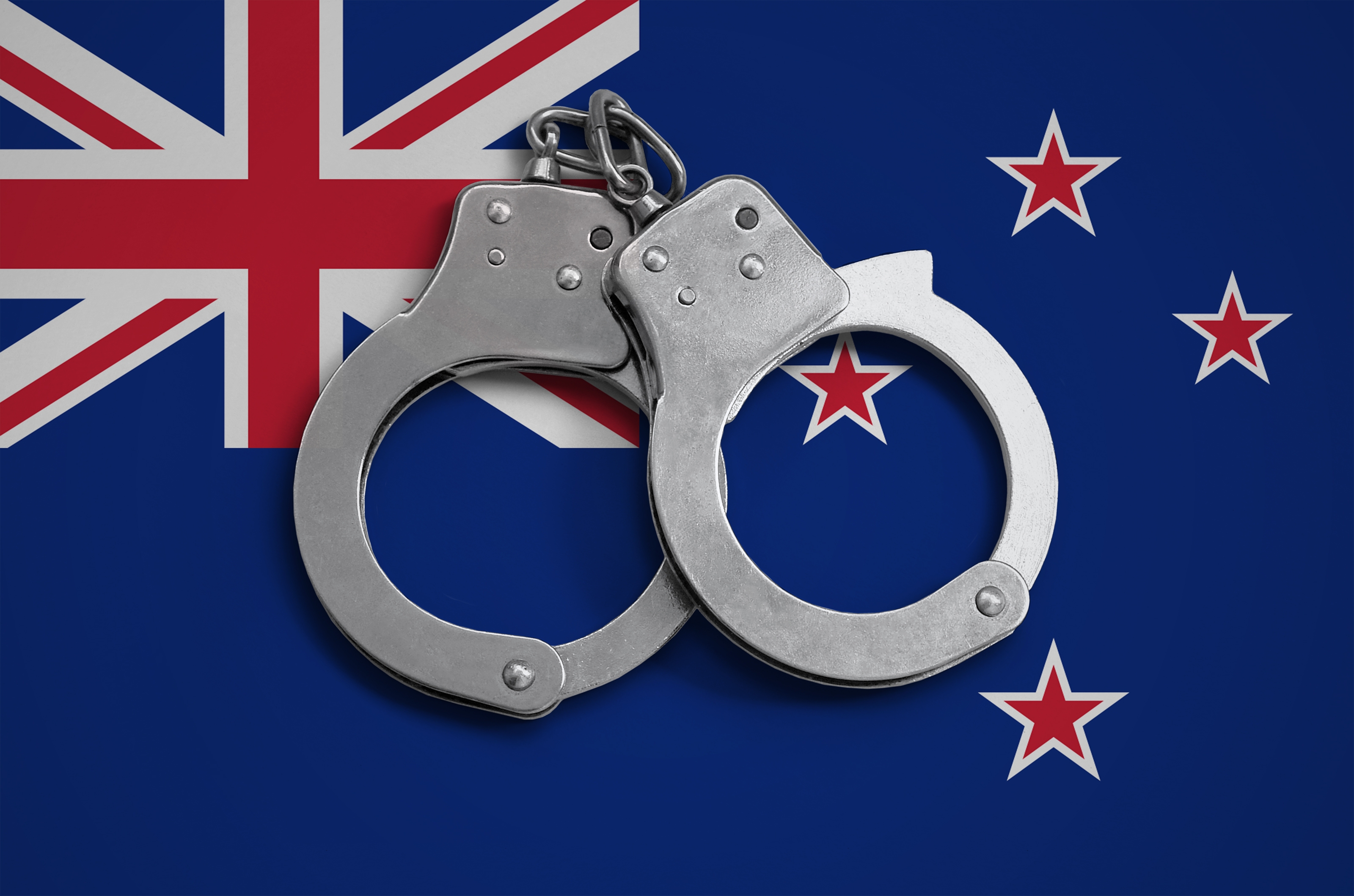 New Zealand flag  and police handcuffs. The concept of observance of the law in the country and protection from crime.